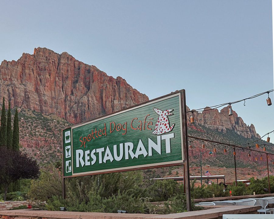 Spotted Dog Café restaurant sign below red rock cliffs