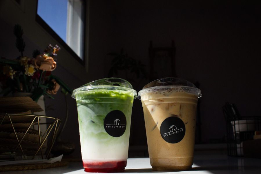 Iced matcha and iced latte in branded cups lit by directional window light