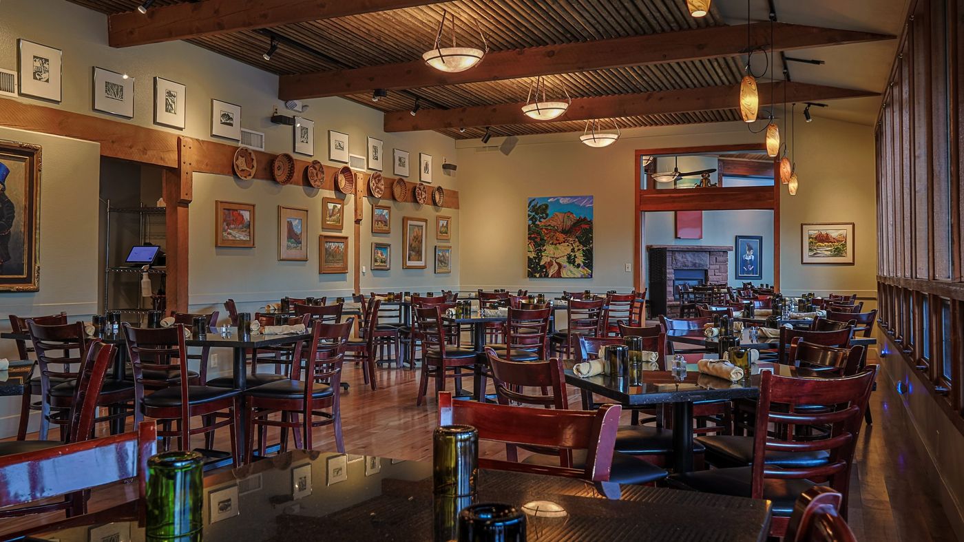 Warmly lit restaurant dining room with timber ceiling, pendant lighting and framed artwork