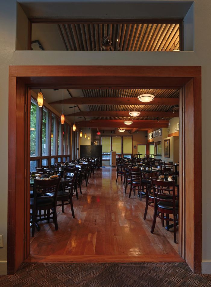 Restaurant dining room seen through a tall timber doorway with polished wood floors